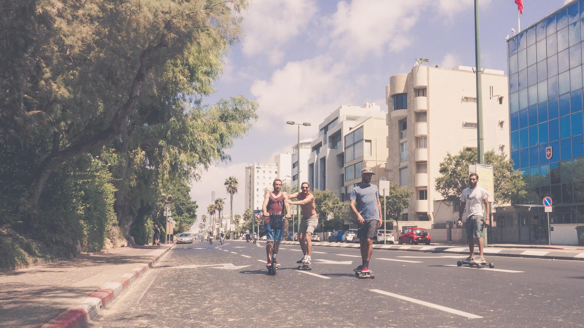Eine Handvoll LGB T-Partoer fahren auf einem Skateboard entlang der Straßen von Tel Aviva.