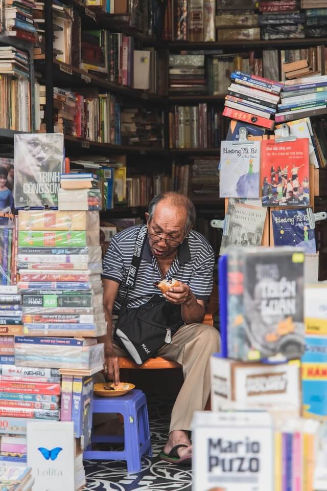 Ein Mann sitzt von Büchern umgeben.