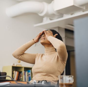 Ein enttäuschter Frauenprogrammierer mit einem Kopf in den Händen sitzt in einem kreativen Büro