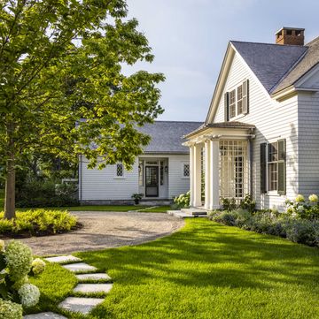 Weißes Haus im Stil eines Cottage mit einem grünen Rasen