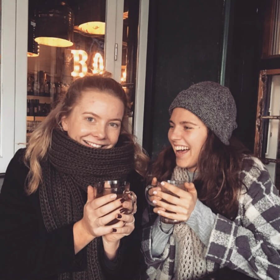 Zwei Mädchen, die in warmen Schals und Jacken gekleidet waren, trinken in einer Bar Glühwein.
