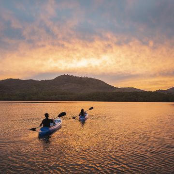 Zwei Menschen fahren bei Sonnenuntergang auf Kajaks in der Lagune